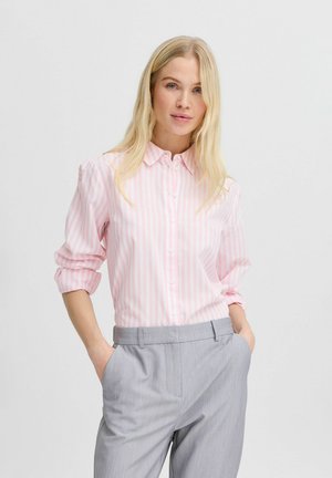 Pink and white striped button-up shirt with a collar and rolled sleeves, paired with gray trousers. Smooth fabric with subtle sheen.