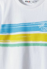 T-shirt en coton blanc avec des rayures horizontales en bleu clair, jaune et vert, avec le texte "SURF" dans une police ludique.