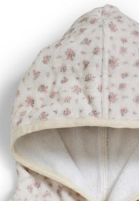 Huvtröja i vit bomull med mjuk textur, med ett rosa blommönster och beige kant vid kanterna.
