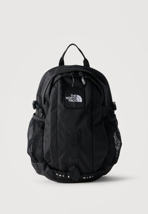 Černý batoh The North Face s logem vpředu, dvěma síťovanými bočními kapsami, předním páskem a horním madlem na jednobílém pozadí.