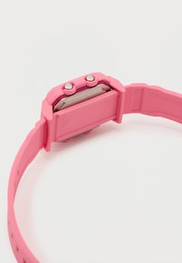 Ροζ ψηφιακό ρολόι χειρός με εύκαμπτο λουράκι, δύο ασημένια κουμπιά στο πλάι και μεταλλικό πίσω κάλυμμα.