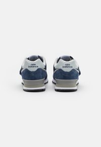 Scarpe sportive in suede blu navy con dettagli bianchi, caratterizzate da una punta arrotondata, un'imbottitura del tallone prominente e una suola testurizzata per una buona aderenza.
