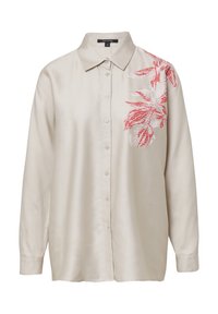 Chemise à manches longues couleur crème avec un col et une broderie florale rouge sur le côté gauche. Confectionnée en tissu lisse, elle est dotée de boutons.