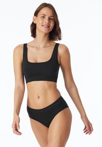 Top cropped nero con scollo quadrato e slip a vita alta coordinati. Tessuto liscio con leggera elasticità e senza hardware o fantasie visibili.