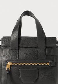 Borsa a mano in pelle nera con finitura a texture, dotata di due manici superiori, una tasca con cerniera dorata e dettagli di cinturino orizzontali.