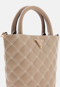 Beige gewatteerde handtas met dubbele handvatten, gouden logo driehoekaccent en contrasterende witte stikdetails. Glad leren textuur.