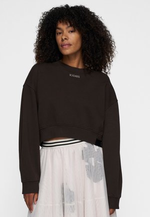 Brown cropped sweatshirt with a round neck and drop shoulders. Features embroidered text "10 DAYS" on the chest. Soft, textured fabric.