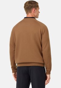 Ruda sportinė palaidinė su raukiniais ant apykaklės ir rankovių, turinti tamsiai mėlyną apykaklę. Minkšta tekstūra, laisvas siluetas ir raglaninės rankovės.