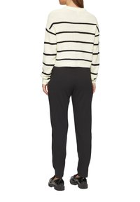 Lichtcrème trui met zwarte horizontale strepen, cropped ontwerp, ribbelstructuur. Gecombineerd met effen zwarte, slim fit broek en glanzende schoenen.