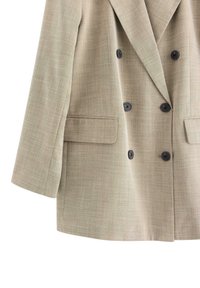 Beige dobbeltræsser blazer med tekstureret stof. Har sorte knapper og to forlommer. Notch-lapel design og struktureret silhuet.