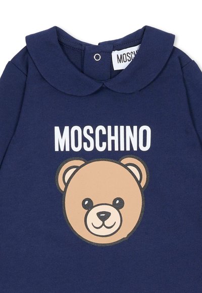 Maglietta in cotone blu navy con collo rotondo, grande grafica di un orso marrone e scritta "MOSCHINO" in bianco sopra l'orso.
