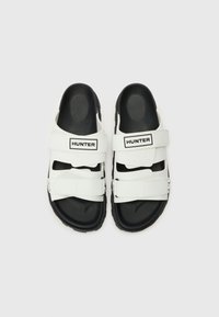 Sandali bianchi con due cinturini regolabili, suola in gomma nera e marchio "HUNTER". Sottopiede texturizzato per comfort e aderenza.