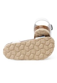 White sandal with a cork ankle strap, flat textured sole in beige, and a streamlined design. Includes a black buckle for adjustment.
