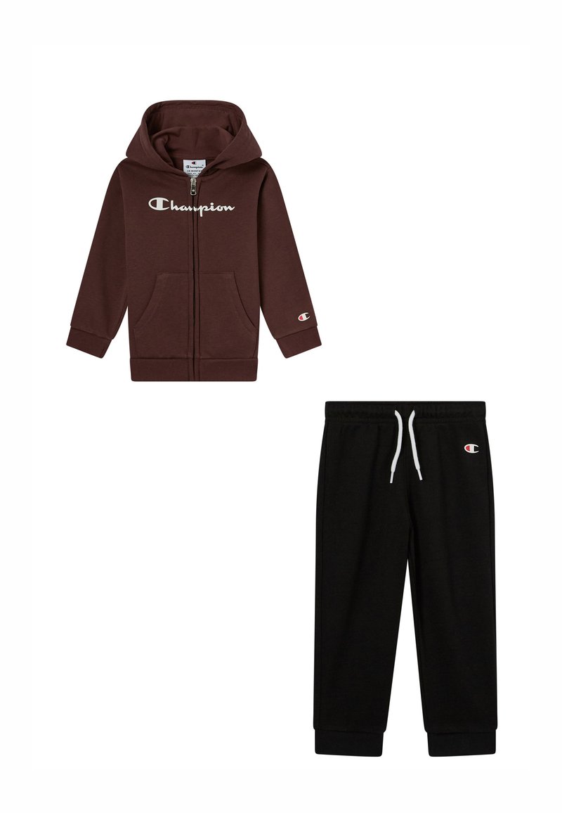 Sudadera marrón con cremallera y bolsillos frontales, y logo blanco; pantalones de chándal negros con cintura elástica y cordón. Ambos son de tejido suave.