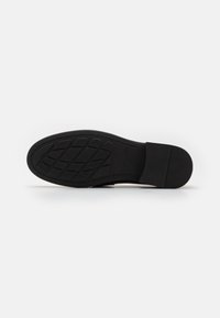 Semelle de chaussure en caoutchouc noir avec un motif de grip texturé et des bords lisses. Bout arrondi et léger talon, conçus pour l'adhérence et la durabilité.