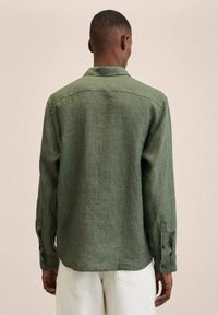 Grünes Leinenhemd mit langen Ärmeln, Rückenpasse und geknöpften Manschetten, mit lockerem Schnitt und strukturierter Stoffqualität.