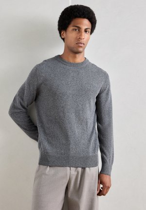 Gray crewneck sweater in a soft, textured knit, featuring long sleeves and a ribbed hem. Worn with light-colored trousers.