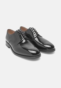 Schwarze Lackleder-Formalschuhe mit Schnürung, abgerundeten Zehen und niedrigen Absätzen, nebeneinander auf einem schlichten weißen Hintergrund gezeigt.