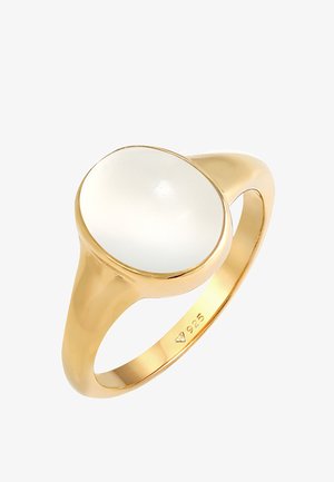 Zelta gredzens ar ovālu baltu akmeni, iestiprinātu gludā ieliktņā. Gredzena josla ir pulēta, ar gravējumu "925" iekšpusē.