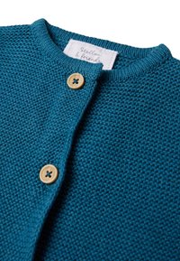 Cardigan lavorato a maglia color teal con un motivo texturizzato, scollatura rotonda e due bottoni in legno sul davanti. L'etichetta riporta "Stellou & Friends."