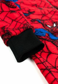 Tessuto in pile rosso con un design di Spider-Man e motivi a ragnatela neri. Include un polsino a coste nere per un ulteriore contrasto e texture.