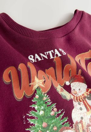 Bordový svetr s kulatým výstřihem, který má vánoční potisk stromečku, sněhuláka a text "Santa's World Tour" v živých barvách.