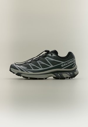 Chaussure de trail running gris foncé avec des accents gris, système de laçage rapide et marquage Salomon sur le côté et la semelle.