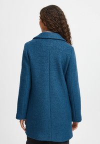 Blauwe wolmix jas met een zachte textuur, brede kraag en lange mouwen. De achterkant heeft een eenvoudig ontwerp en een rechte snit.