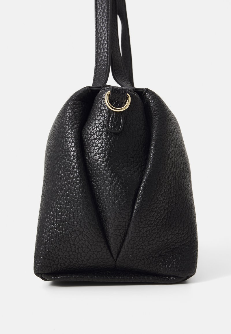 Borsa a mano in pelle nera con una finitura testurizzata. Presenta un'accento in metallo dorato e una forma unica, che si restringe alla base.