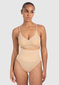 Naadloze nude bh met verstelbare bandjes en een bijpassende hoge taille slip. Kenmerkt een gladde textuur en subtiele geribbelde patronen.