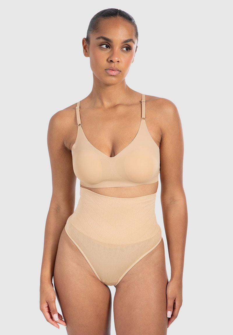 Naadloze nude bh met verstelbare bandjes en een bijpassende hoge taille slip. Kenmerkt een gladde textuur en subtiele geribbelde patronen.