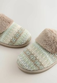Chaussons tricotés avec un motif crème et vert pastel, dotés d'un doux revers en fausse fourrure beige et d'une semelle plate en caoutchouc.