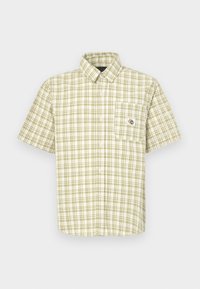 Beige og hvit kortermet rutet skjorte med knapper, med lomme foran til venstre som har en liten sol- og måne-patch.