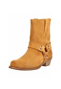 Bota de ante marrón claro hasta el tobillo con un tacón bajo de madera y una correa decorativa con remaches plateados alrededor del tobillo.