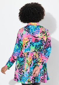 Robe à manches longues colorée présentant un motif abstrait vibrant de rose, bleu, vert et noir. Design évasé avec une jupe plissée.