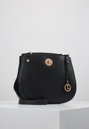 Musta nahkainen olkalaukku, jossa on kultainen pyöreä lukko ja logoriipus, kaarevat reunat ja säädettävä hihna valkoisella näyttöpinnalla.