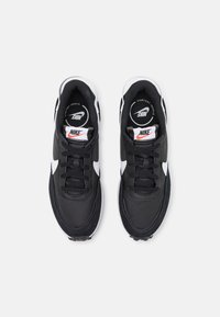 Sneakers neri con accenti bianchi, dotati di una parte superiore in tessuto testurizzato, design con lacci e una soletta imbottita. Logo Nike sulla linguetta.