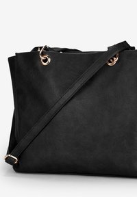 Borsa tote in pelle sintetica nera con texture liscia, dotata di dettagli in hardware rosa dorato e di una lunga tracolla regolabile.