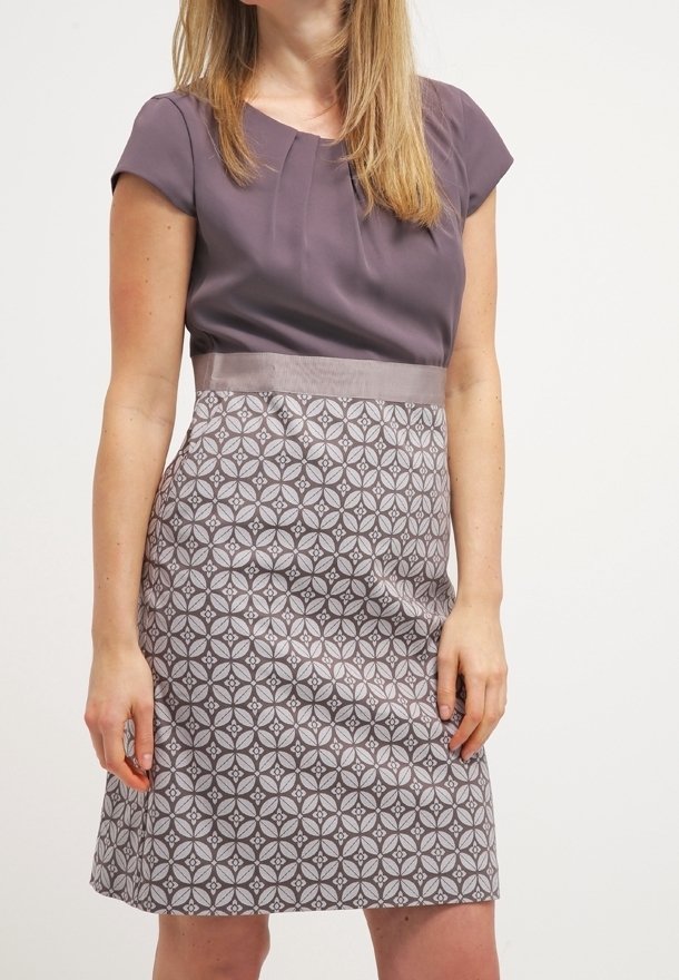Korte mouwen jurk met een effen paarse top, een gestreepte grijze rok met geometrische ontwerpen en een satijnen gordel rond de taille.