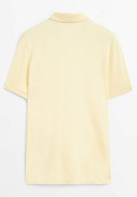 Polo jaune clair uni à manches courtes avec col, montré de dos sur fond blanc.