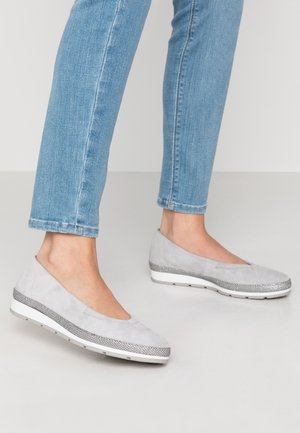 Lysegrå ruskind kilehælede sko med tekstureret sølvbåndsdetalje båret med lyseblå smalle jeans på en glat lys gulv.