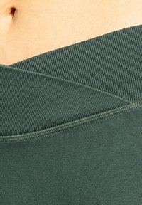 Groene katoenblend stof met een getextureerde geribde tailleband. Het ontwerp heeft een gelaagde uitstraling met gladde afwerkingen en contrasterende stiknaden.