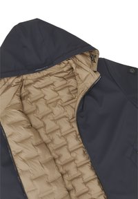 Schwarze Kapuzenjacke mit beige gestepptem Isolierfutter und vorne teilweise geöffnetem Reißverschluss, der die inneren Nähdetails zeigt.