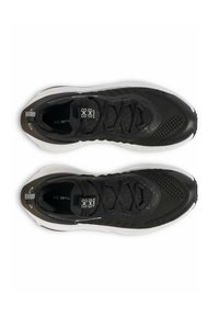 Baskets de sport noires avec un dessus en maille texturée, dotées de lacets noirs, d'une semelle rembourrée et d'accents blancs sur les bords extérieurs.