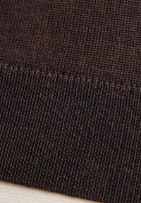 Tessuto lavorato a maglia marrone caratterizzato da una texture liscia con una tessitura stretta. Il bordo presenta un motivo a coste, che si fonde in un colore più chiaro al di sotto.