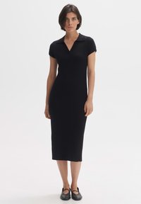 Abito midi nero a costine con maniche corte e collo. Presenta una silhouette aderente e un orlo dritto, realizzato in un tessuto elasticizzato.