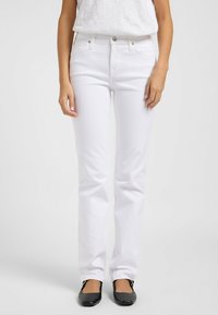 Jeans de mezclilla blanca de pierna recta con cinco bolsillos, cierre frontal de botones y una textura suave, combinados con bailarinas negras.