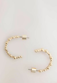 Goldene Creolen mit einem strukturierten Design und runden Akzenten, die eine geschwungene Form betonen und über einen sicheren Steckverschluss verfügen.
