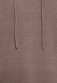 Felpa marrone con una lavorazione a maglia texturizzata, dotata di due cordini. Il tessuto sembra morbido e accogliente, adatto per un abbigliamento casual.