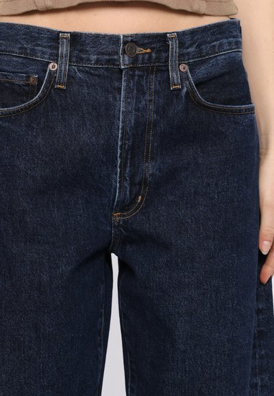 Dunkelblaue Denim-Jeans mit geradem Schnitt, ausgestattet mit Vordertaschen, einem Knopfverschluss und kontrastierenden orangefarbenen Nähten entlang der Nähte.